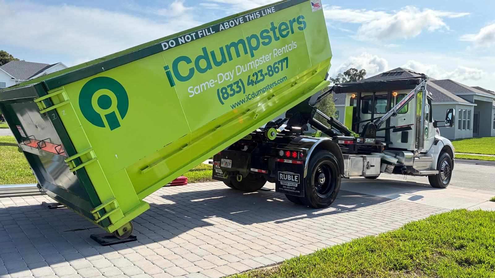 Close-up of Rolliskate official underlayment protecting a customer driveway while a roofing dumpster is being loaded with shingles