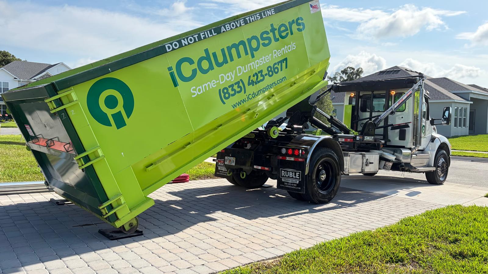 iCdumpsters delivery truck placing a roofing dumpster with Rolliskate driveway protection on a customer property in Central Florida