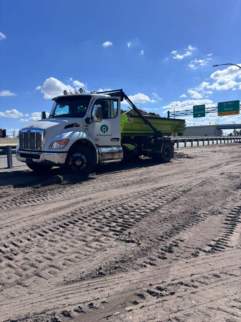 iCdumpsters Peterbilt roll-off truck delivering a same-day dumpster rental in Orlando for a public-works contractor near the I-4 Tampa interchange